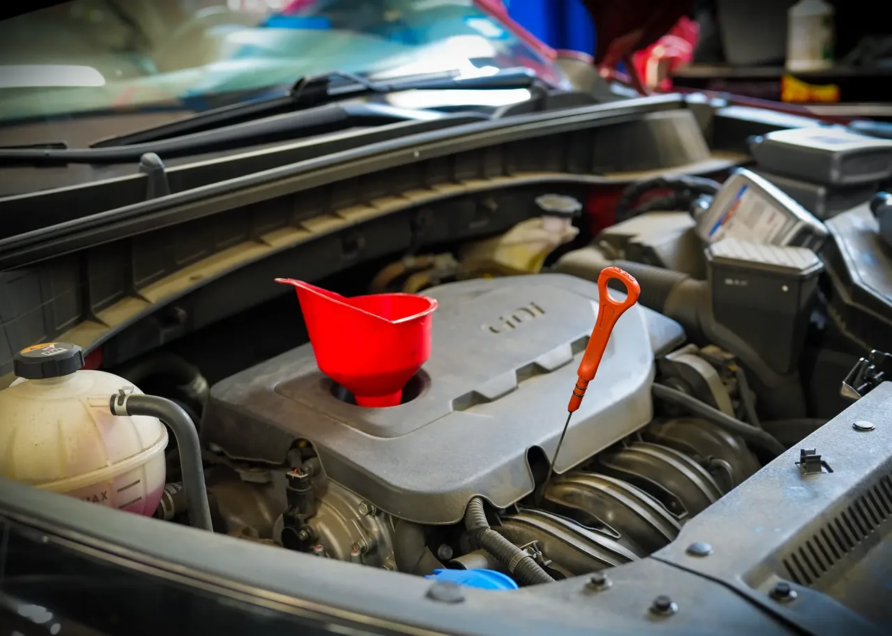 Queens Auto Repair engine maintenance with a red funnel in the engine bay