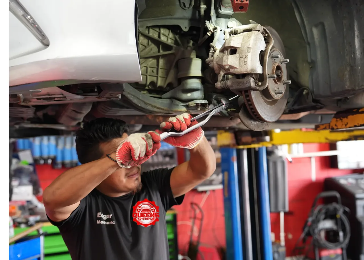 Queens Auto Repair mechanic servicing brakes on a vehicle lift